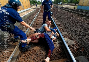 Syrian couple protecting their child from Hungarian police trying to drag the family back into the internment camp for Syrian refugees