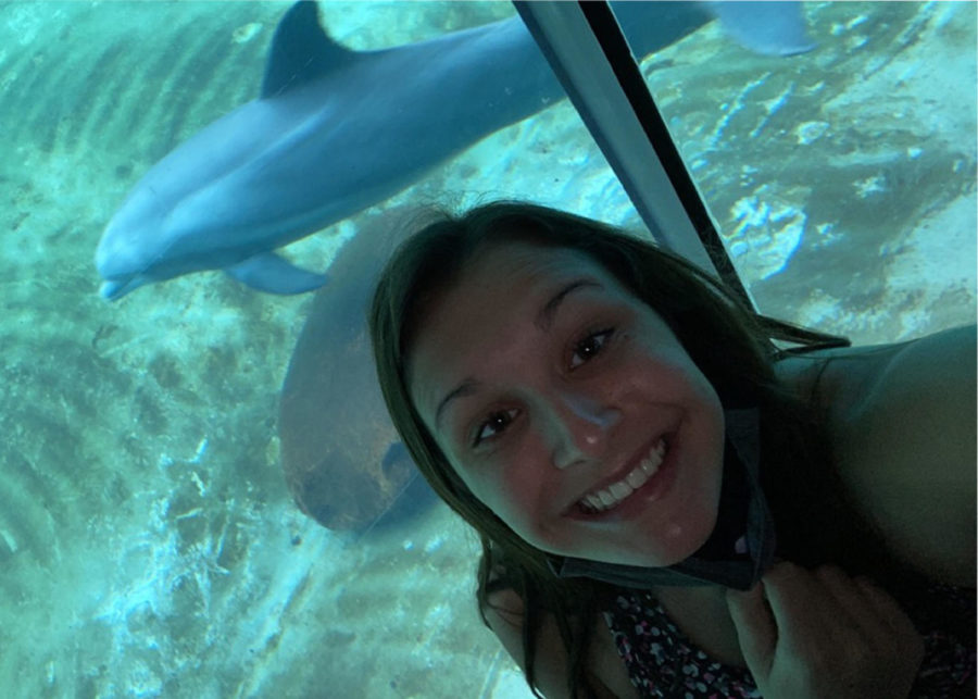 Kaelin Coffin taking a picture on vacation with dolphins. 