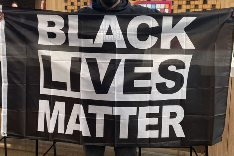 Student holds black lives matter flag before walking out of the building.
