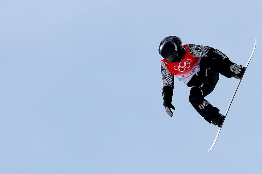Shaun white mid flight on the halfpipe at the Winter Olympics.
