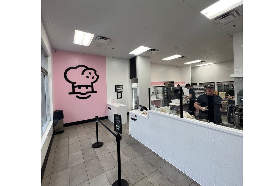 Inside the Crumbl Cookie store where you can see the logo and the kitchen where they made the cookies.