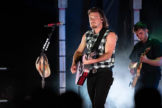 In less than five years, Morgan Wallen has propelled from a  country music singer to a global superstar. Morgan Wallen performing at Freedom Fest 2019 by Robert Vicens is licensed under Creative Commons License.